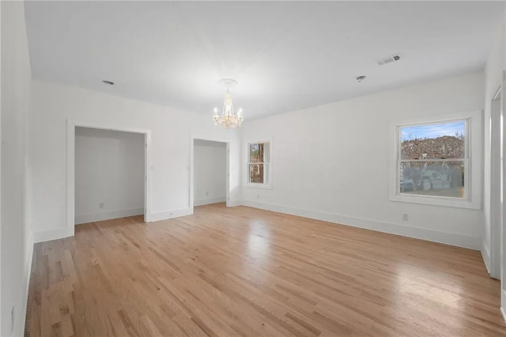 Unfurnished room featuring a healthy amount of sunlight, a notable chandelier, and light hardwood / wood-style floors