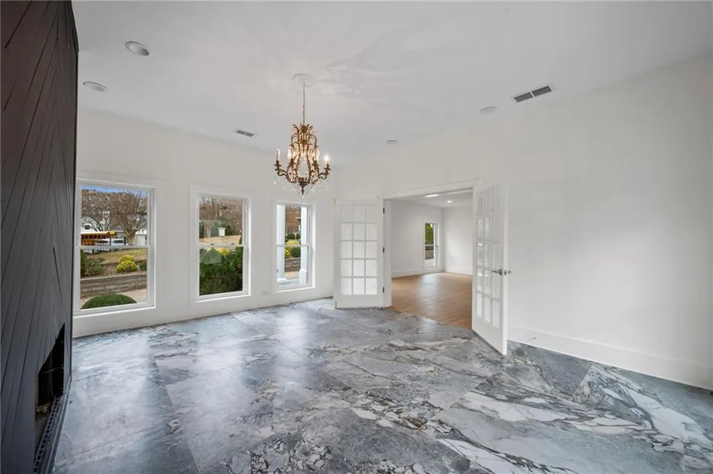 Unfurnished room with french doors and a notable chandelier