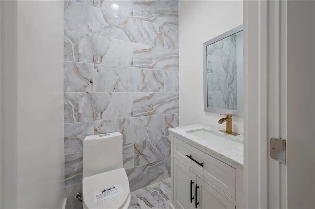 Bathroom featuring vanity, tile walls, and toilet
