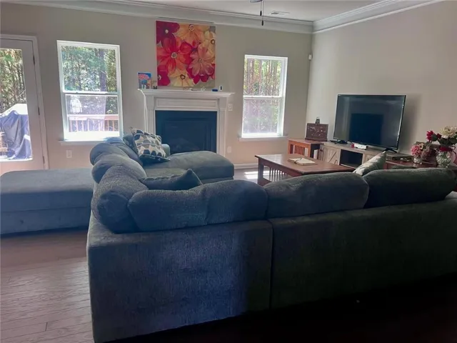 Spacious room featuring wood-finish flooring and a white mantel fireplace