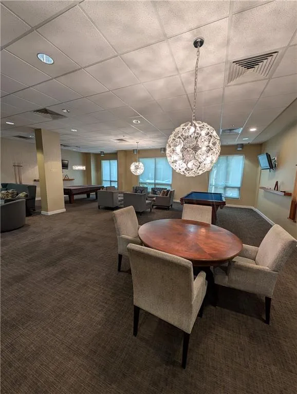 Carpeted dining space featuring billiards and a paneled ceiling
