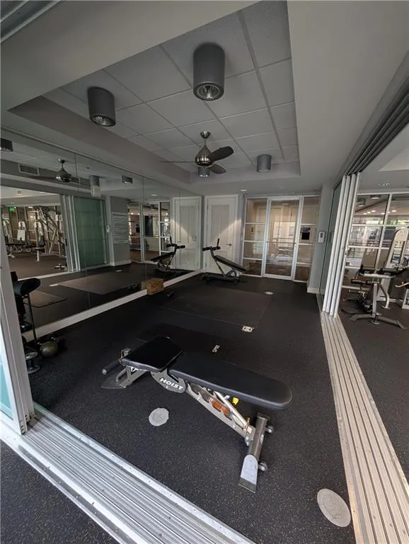 Workout area with a ceiling fan and a raised ceiling