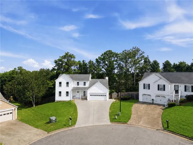 Two-story white residence featuring a two-car garage, concrete driveway, and a covered front entry