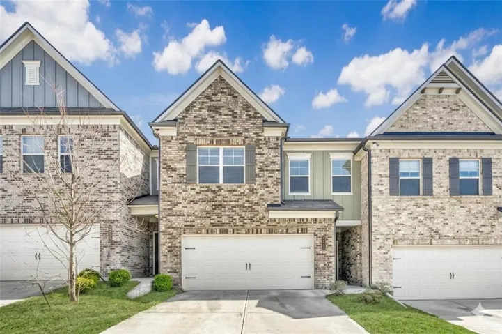 Brick and siding townhome featuring an attached two-car garage, concrete driveway, and front entryway