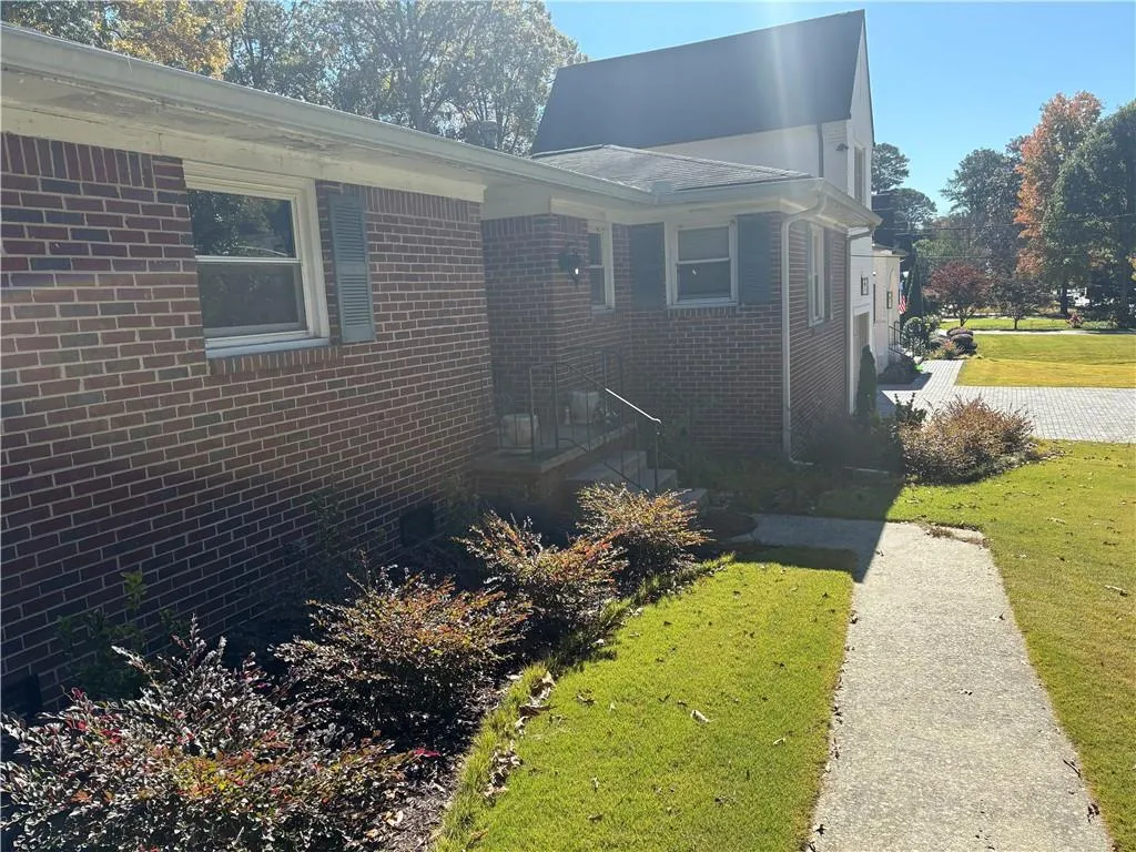 View of side of home featuring brick siding, a lawn, and crawl space