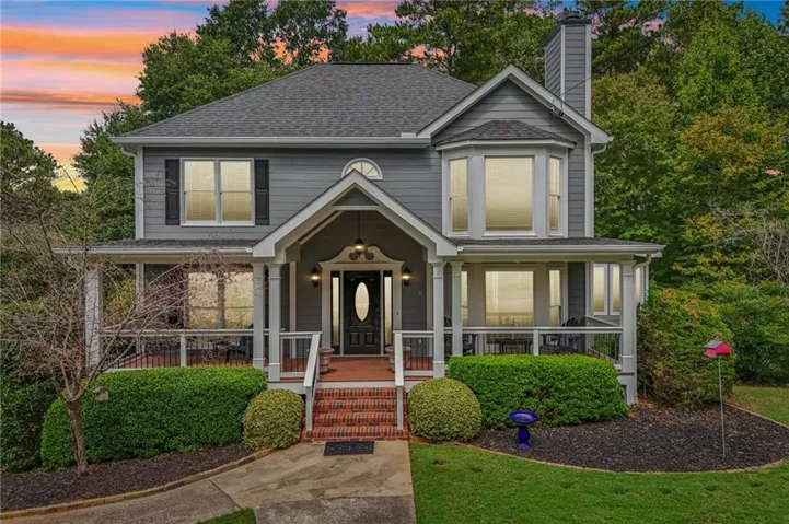 Two-story residence featuring a covered front porch, bay window, and a dark asphalt shingle roof