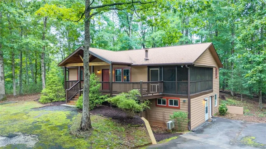 Two-story residence featuring a covered front porch, an exterior deck, and an enclosed screened porch