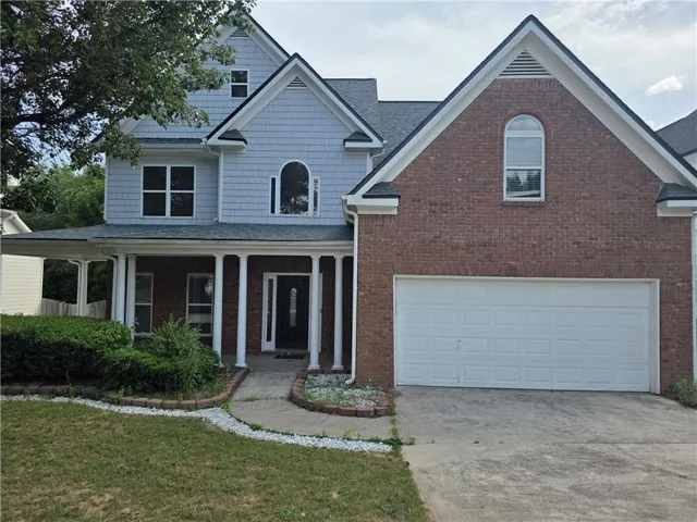 Brick and shingle exterior with a covered porch featuring columns