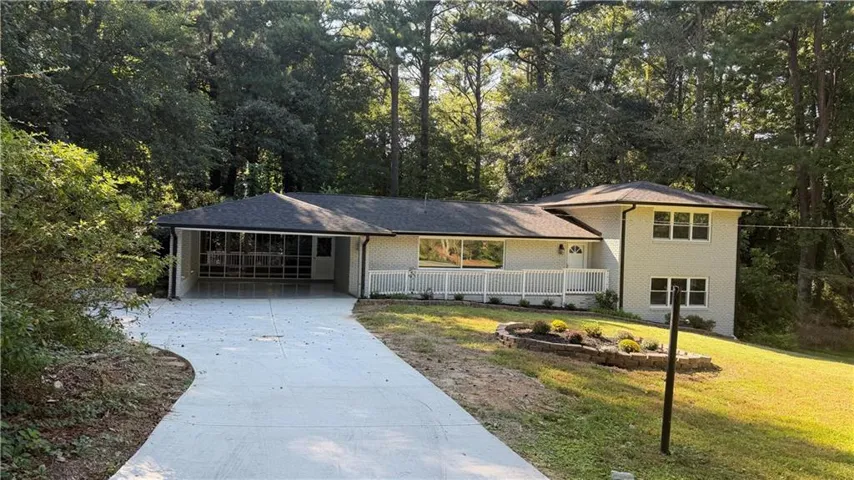 Exterior featuring a light-colored facade, dark shingle roof, a covered carport, and a white railing porch