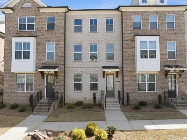 Three-story townhome featuring a brick facade and multiple windows