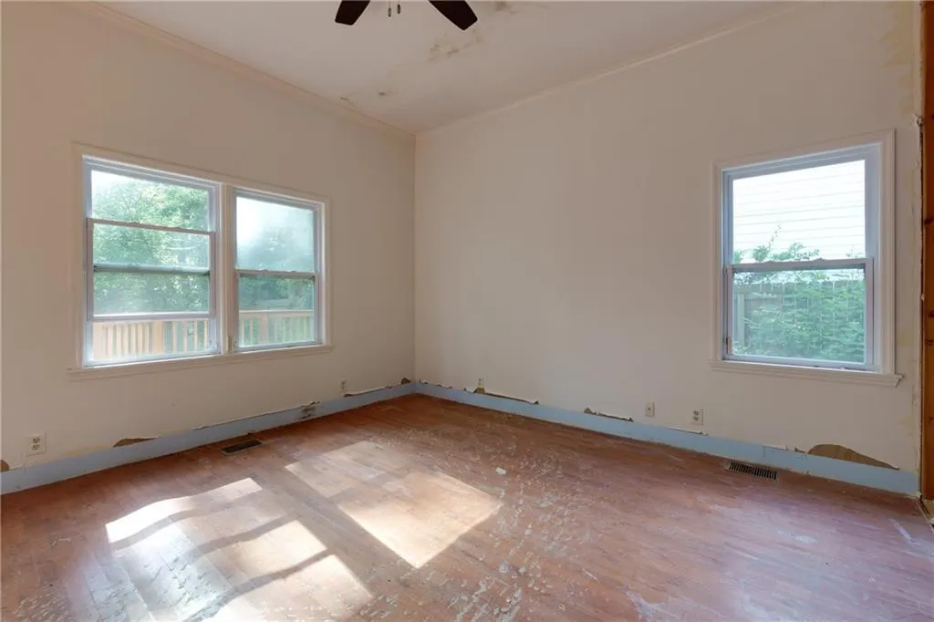 Unfurnished room with healthy amount of natural light, ceiling fan, light wood-type flooring, and crown molding
