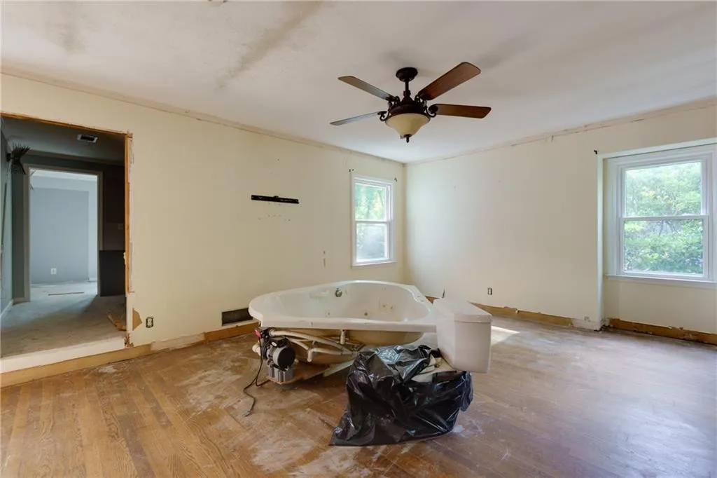 Bathroom with wood finished floors, a ceiling fan, and a tub with jets