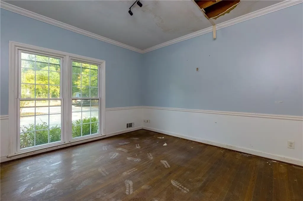 Empty room with healthy amount of natural light, hardwood / wood-style flooring, and crown molding