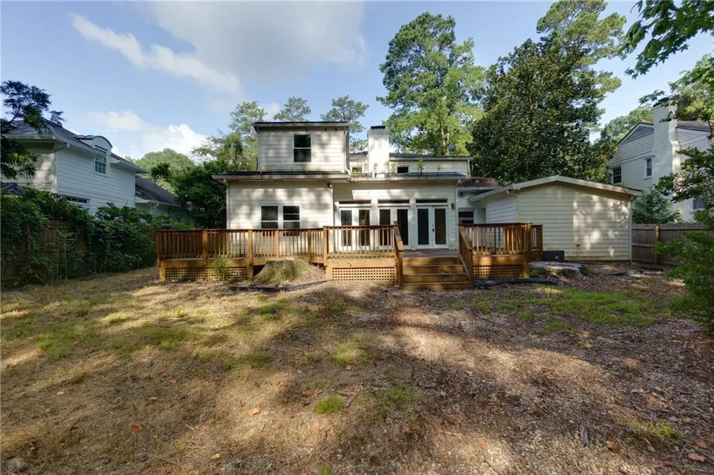 Rear view of house with a chimney, a deck, and french doors