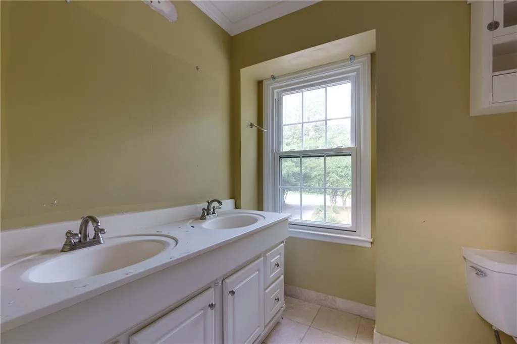 Bathroom with tile patterned floors, crown molding, and double vanity