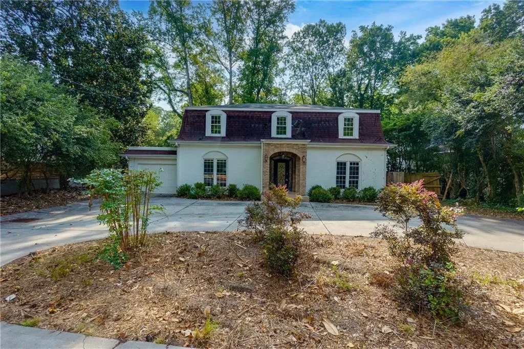 View of front of house with mansard roof, a shingled roof, driveway, and a garage