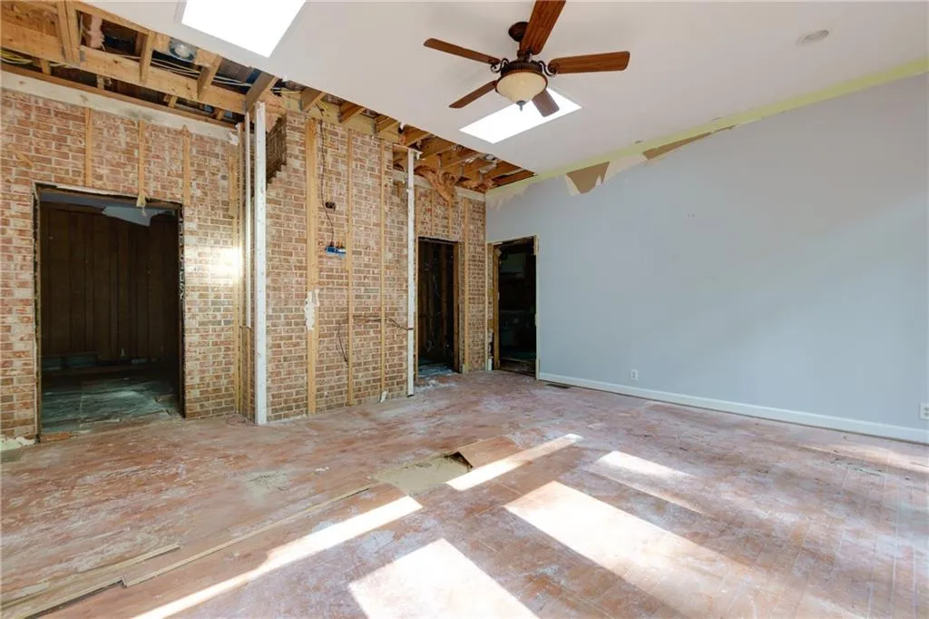 Empty room featuring brick wall, a ceiling fan, and a towering ceiling