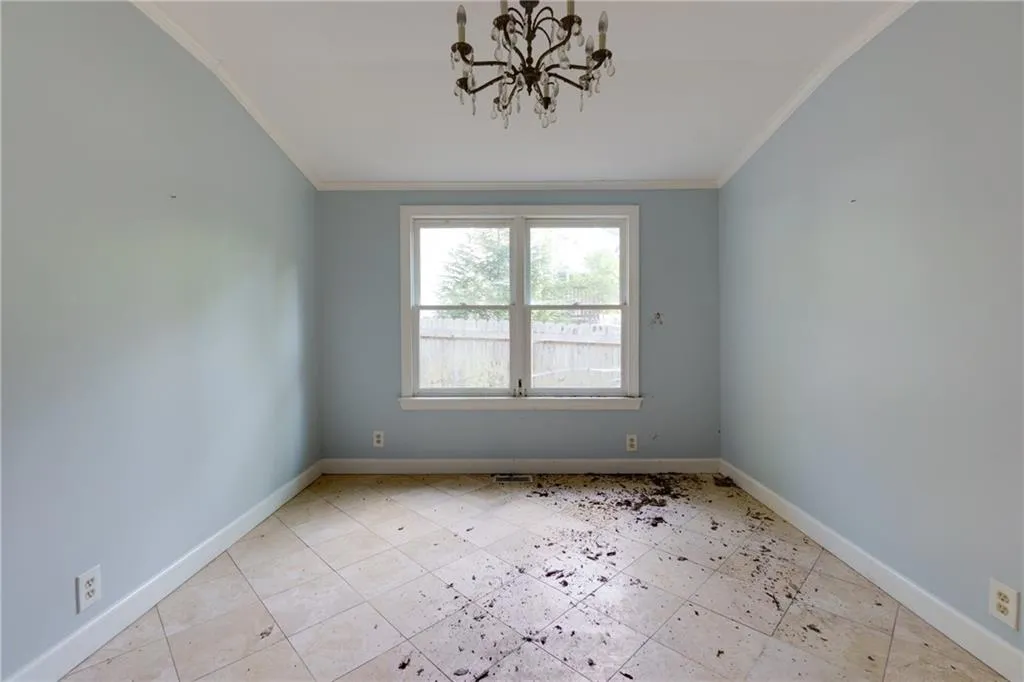 Tiled spare room with crown molding and a chandelier
