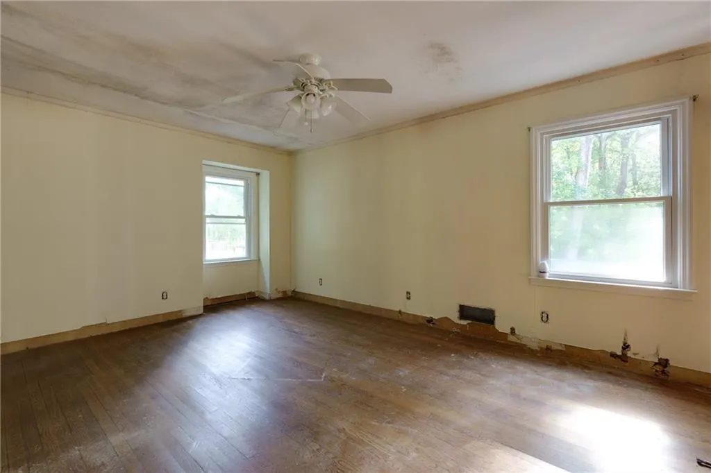 Empty room with hardwood / wood-style flooring, ceiling fan, and crown molding