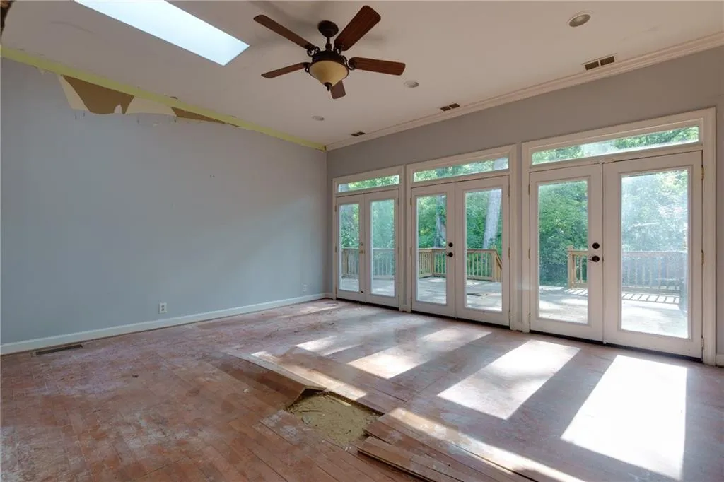 Empty room featuring french doors, healthy amount of natural light, ornamental molding, hardwood / wood-style flooring, and ceiling fan