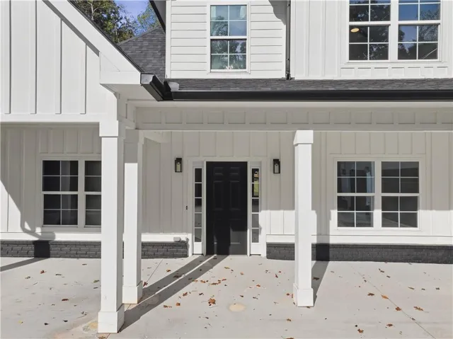 White board and batten siding, black asphalt shingle roof, black front entry door, black exterior light fixtures, and white-framed windows
