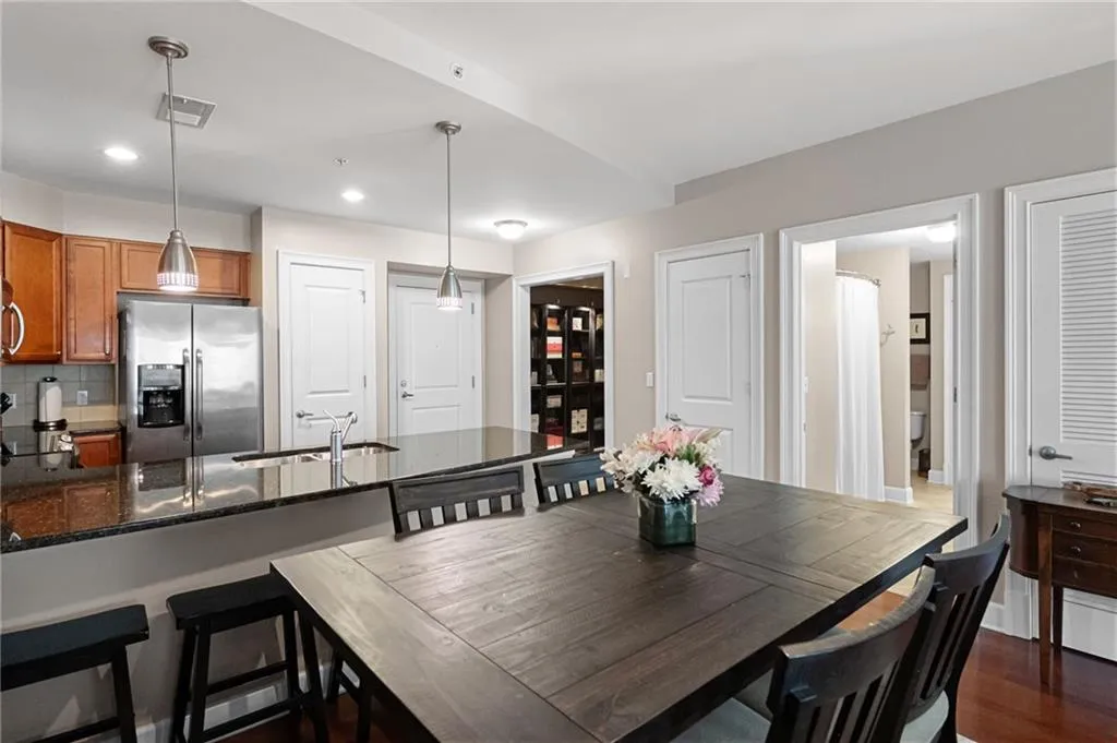 Kitchen with dark hardwood / wood-style flooring, backsplash, sink, stainless steel fridge with ice dispenser, and hanging light fixtures