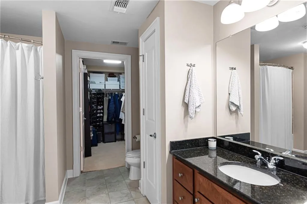 Bathroom featuring toilet, tile floors, and vanity with extensive cabinet space