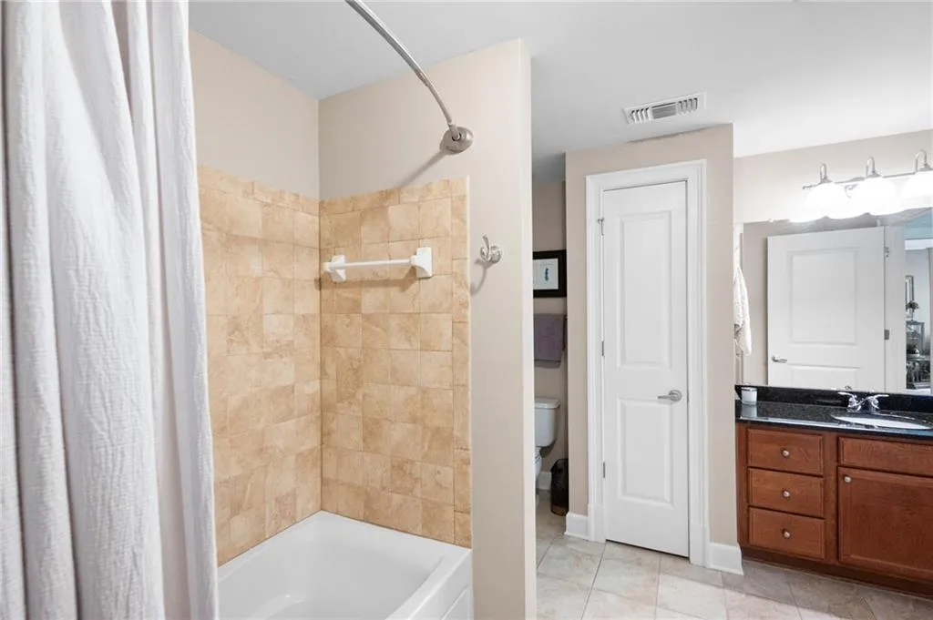 Full bathroom featuring tile floors, toilet, vanity, and shower / tub combo with curtain