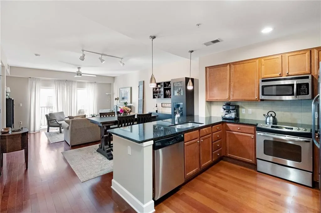 Kitchen with decorative light fixtures, appliances with stainless steel finishes, light hardwood / wood-style flooring, track lighting, and ceiling fan