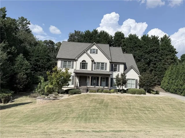 Traditional-style exterior with light-colored siding, dark shutters, a covered front porch, and a multi-level roofline