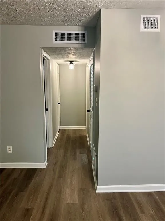 Corridor featuring wood finished floors and a textured ceiling