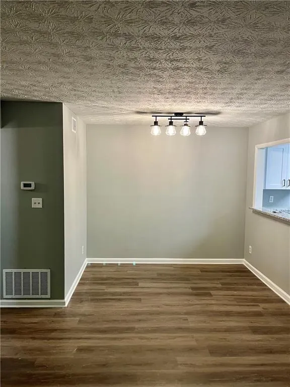 Spare room with wood finished floors and rail lighting