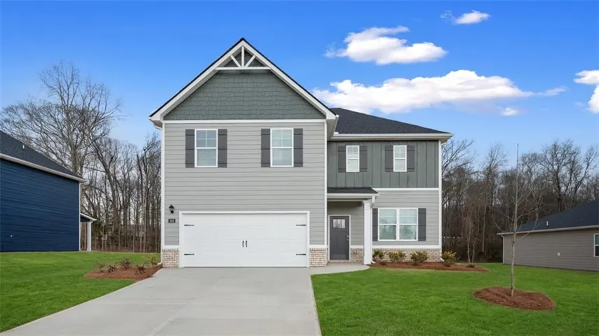 View of front of house with a front yard, a garage, driveway, and board and batten siding