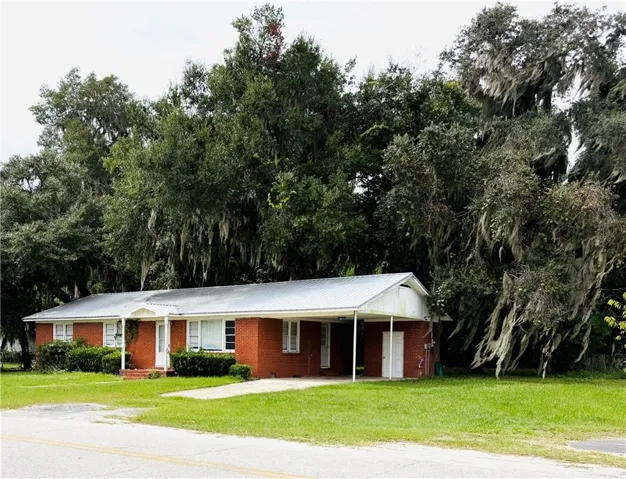 Ranch-style house with a front yard, brick siding, and a carport