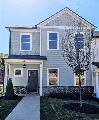Two-story exterior featuring light blue siding, gray shingle accents, black brick detailing, a covered entry, and a dark front door with glass inserts