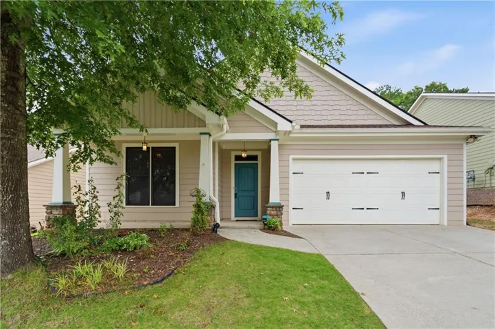 Siding exterior with decorative shake accents, an attached two-car garage, concrete driveway, covered porch with stone-wrapped columns, and a vibrant teal entry door