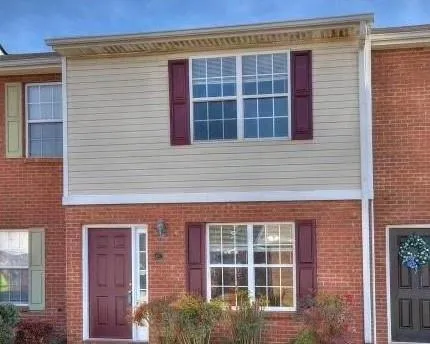 Brick and siding exterior with a paneled entry door, transom window, and exterior wall sconce