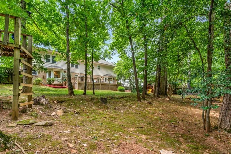 Rear view of back yard shows level play space as well as tons of shade and trees.