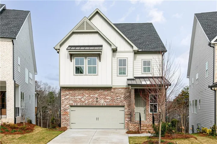 View of front of home featuring board and batten siding, brick siding, a standing seam roof, and concrete driveway