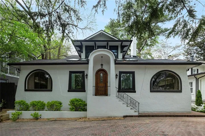 White stucco exterior with an arched entryway, dark wood front door, and decorative iron railings