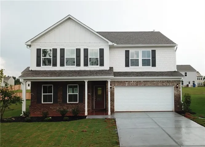 Two-story residence featuring a brick and white shingle facade, a covered front porch with white columns, and a two-car garage