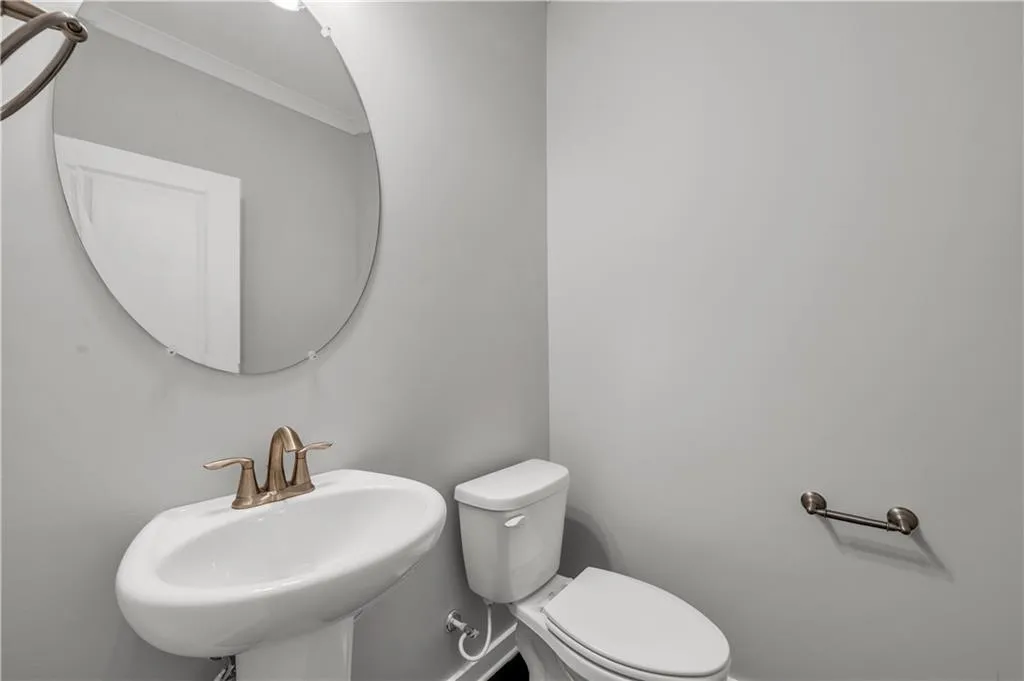 Half bathroom featuring ornamental molding and a sink