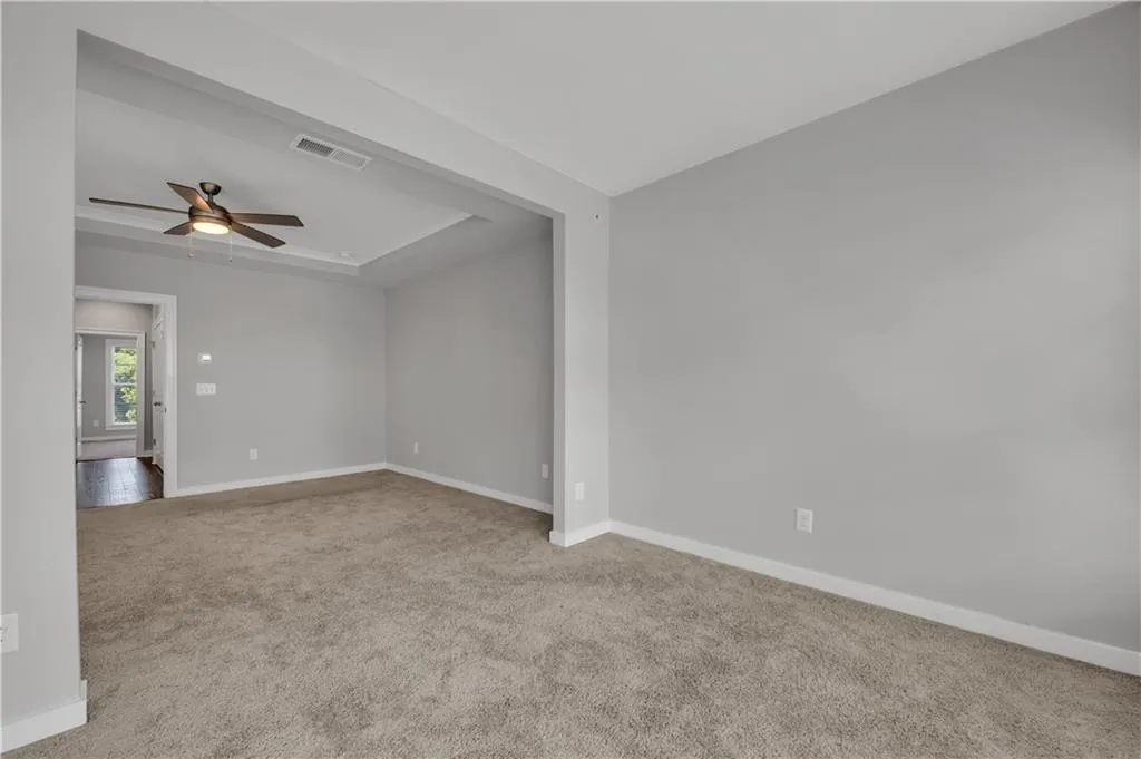 Spare room with carpet floors, ceiling fan, and a raised ceiling