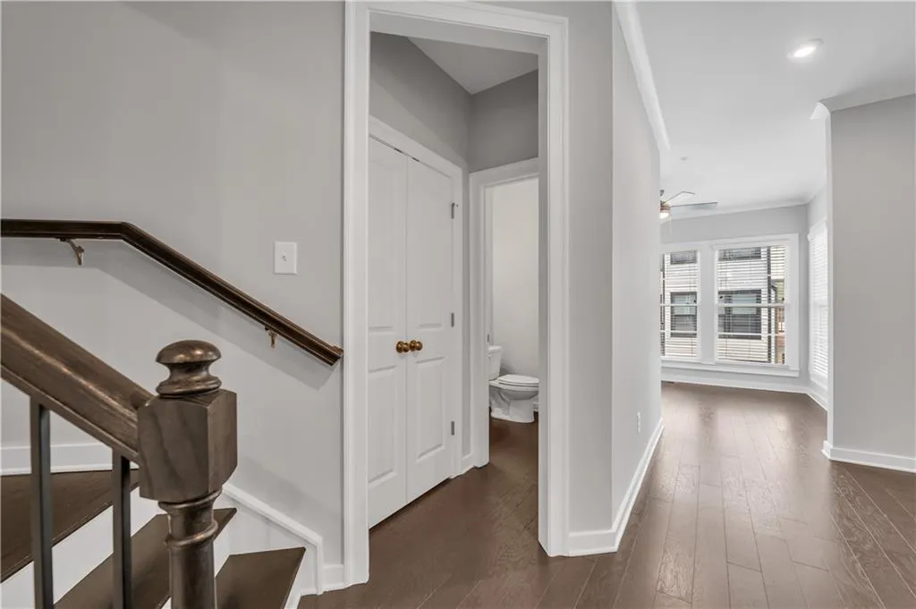Corridor with crown molding, dark wood-type flooring, recessed lighting, and an upstairs landing