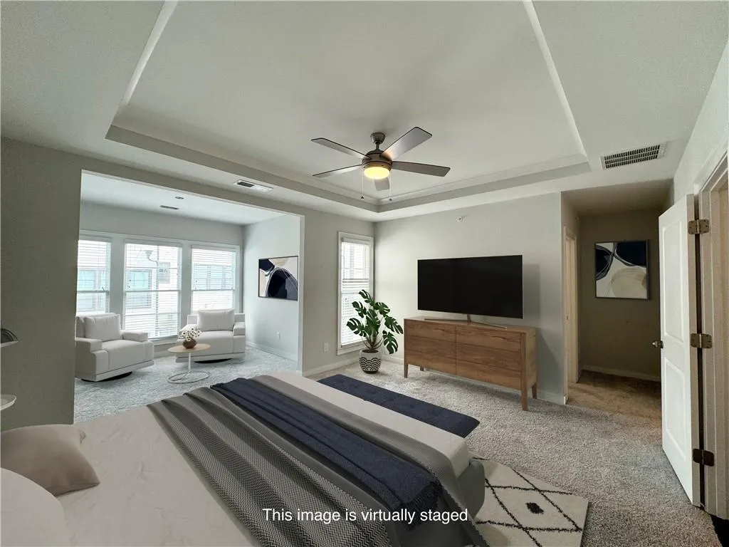 Bedroom featuring a tray ceiling, carpet, and a ceiling fan