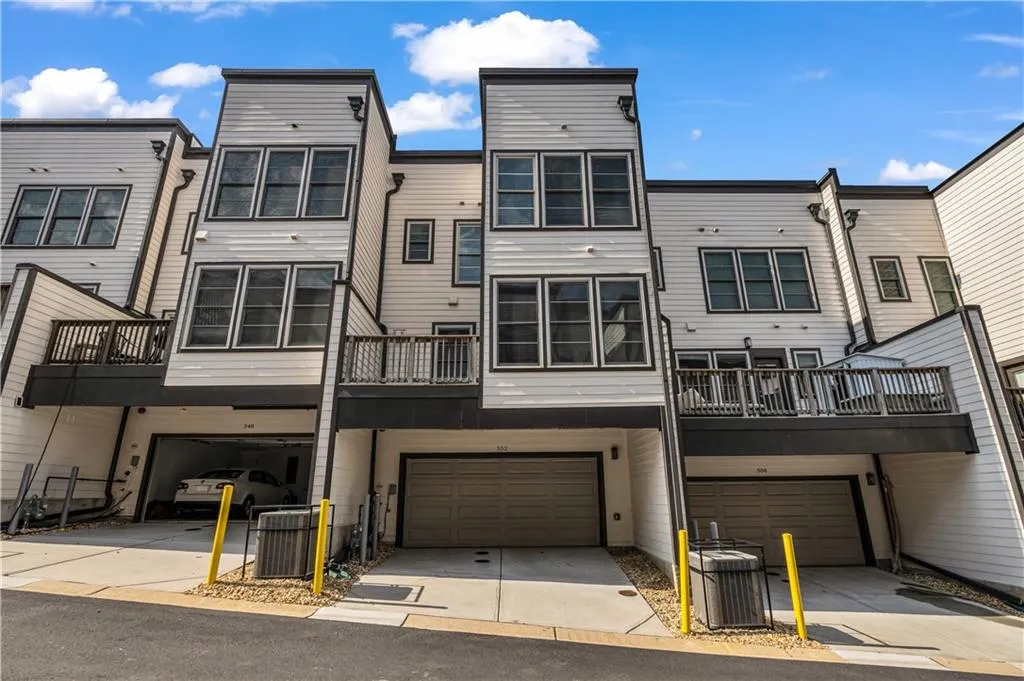Back of house with an attached garage, driveway, and a balcony