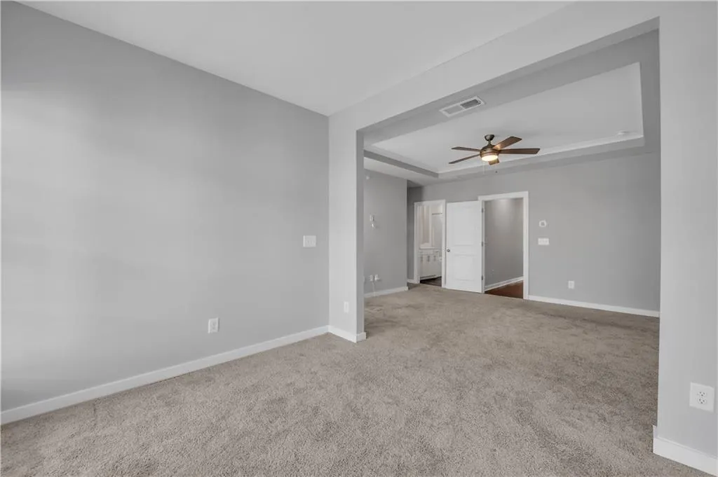 Carpeted empty room with a ceiling fan and a tray ceiling