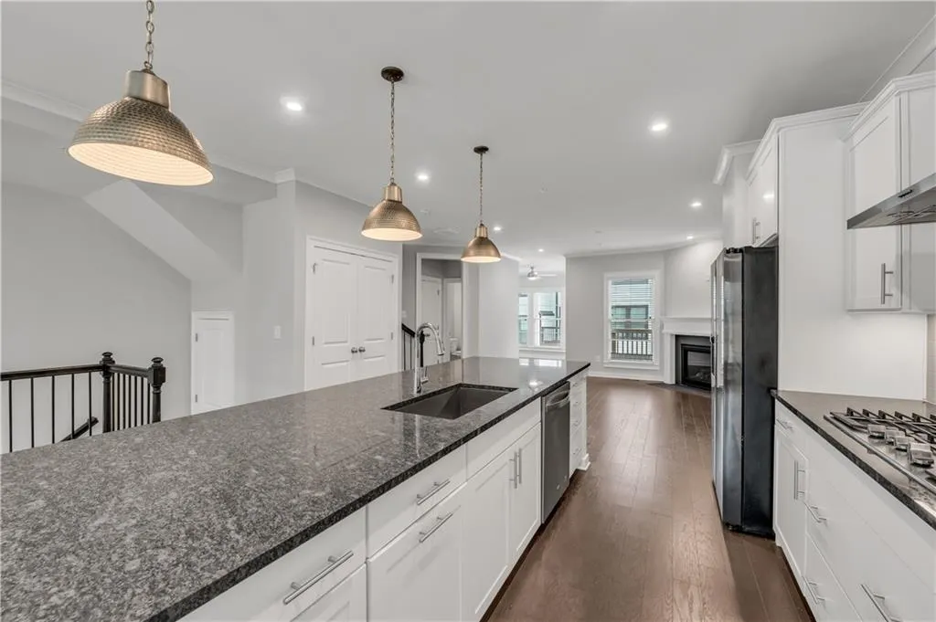 Kitchen with stainless steel appliances, white cabinets, recessed lighting, dark wood-style floors, and pendant lighting