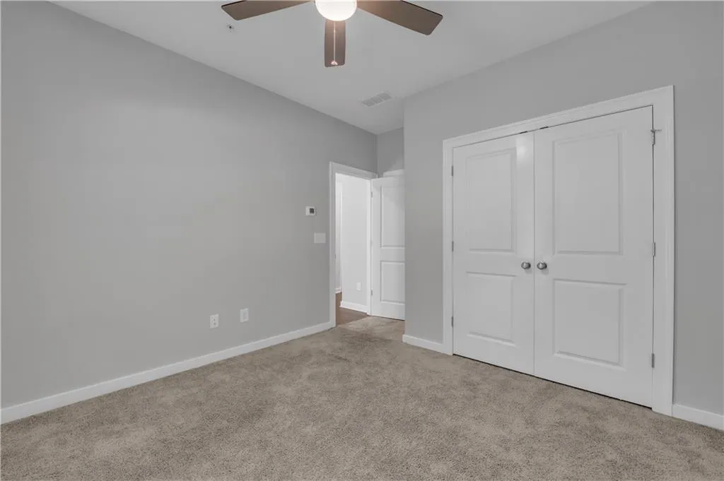 Unfurnished bedroom with carpet, a closet, and ceiling fan