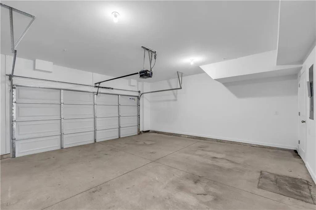 Garage featuring a garage door opener and baseboards